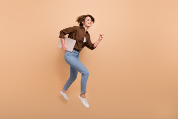 Poster - Full length photo of pretty positive girl dressed brown shirt jumping high holding gadget empty space isolated beige color background