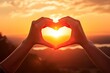 © BetterPhoto - A beautiful sunset with two hands holding each other in the shape of a heart.