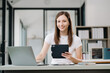 © Nuttapong punna - Confident business expert attractive smiling young woman holding digital tablet  on desk in office..