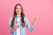© deagreez - Photo portrait of attractive young woman hold device point look empty space dressed stylish denim clothes isolated on pink color background