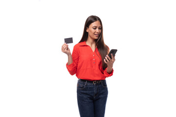 Wall Mural - young model woman with straight black hair dressed in a red shirt holding a plastic card and a smartphone