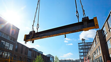 A truck crane lifts a large steel beam on a construction site. Real estate construction process.