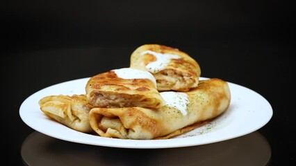 Wall Mural - Thin fried pancakes with meat filling in a plate with sour cream and spices.