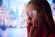 © master1305 - Little girl, child standing outdoors with shocked and excited face. Christmas tree with lights reflecting on kid's eyeglasses. Concept of Christmas, childhood, dreams, fantasy, happiness, inspiration
