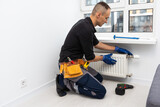 Fototapeta Łazienka - Professional plumbers installing new heating radiator in room