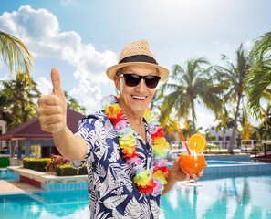 Poster - Senior tourist holding a cocktail and giving a thumb up by a swimming pool