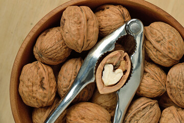 Wall Mural - Walnuts in wooden bowl with metal nutcracker and heart shaped walnut