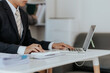 © NanTua - Asian male businessman working with laptop computer and smart phone with accounting documents at table in office Happy man working concept