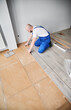 © anatoliy_gleb - Man in workwear measuring distance from wall to laminate board with measuring tape ruler. Male construction worker using tape measure while installing laminate flooring in apartment under renovation.