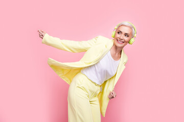 Canvas Print - Portrait of energetic aged business lady loves music during working time listen headphones and dancing isolated over pink color background