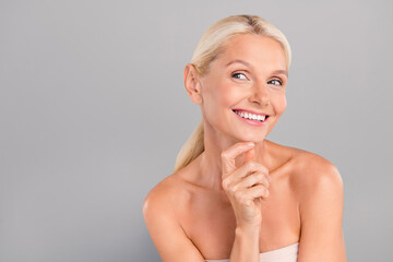 Poster - Portrait of cheerful happy lovely lady touch chin interested look empty space skincare products offer isolated on gray color background