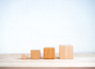Poster - from small to big. the power of micro goals, business concept. four sizes of empty wooden cube block