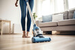 Close up photo of a woman vacuuming floor with a vacuum cleaner