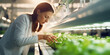 Junge Frau kontrolliert das Wachstum der Pfalnzen im Bereich Vertical Farming