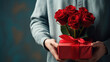 Man holding a bouquet of red roses in one hand and a gift box with a red ribbon in the other, suggesting a romantic gesture or celebration.