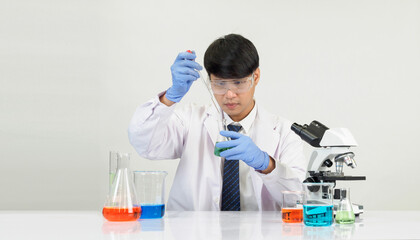 Wall Mural - Portrait Asian man student scientist Wearing a doctor gown in the lab looking hand at chemist. caused by mixing reagents in scientific research laboratories with test tubes and microscope on the table