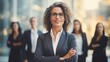 © Hope - Determined to make it no matter the cost. Shot of an attractive mature businesswoman standing with business team behind with her arms folded on office background