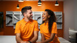 © Favio - two store clerks, white man and African American woman, smiling and dressed in orange