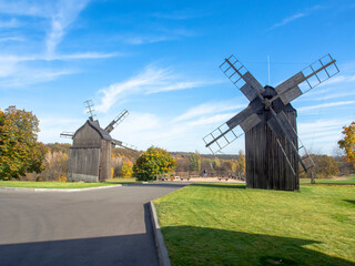 Old wooden windmill in field with green grass and blue sky, sunny day.