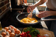 © Marko Geber - Woman hand Seasoning Scrambled Eggs on Stove in a Skillet