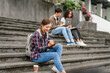 © M+Isolation+Photo - Happy diverse university students sitting on steps, using laptops and tablets, enjoying conversation. Student exchange and study abroad program, Asian man, african american woman and caucasian people.
