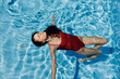 © SHOTPRIME STUDIO - Happy woman swimming in the pool in red swimsuit with loose long hair relaxed in the sunshine, skin protection with sunscreen, concept of relaxing on vacation in tropical climate, lifestyle.