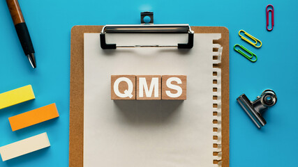 Wall Mural - There is wood cube with the word QMS. It is an abbreviation for Quality Management System as eye-catching image.