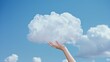 A human hand holds a cloud. Touch in the sky. Soft and fluffy cloud in a clear blue sky