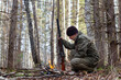 The hunter squatted down by a small fire in the forest