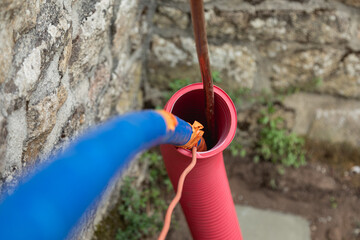 Des tuyaux destinés au transport de fluides caloporteurs insérés dans une gaine de protection rouge, dans le cadre de l'installation d'un système solaire thermique pour l'eau chaude.