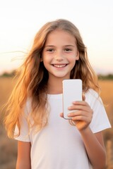 Poster - A young girl holding a cell phone in a field. Perfect for illustrating technology and communication in outdoor settings