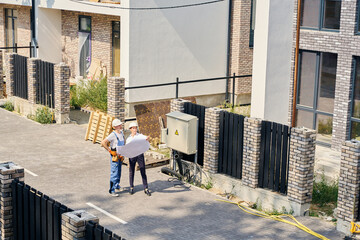 Construction manager inspecting development site together with builder