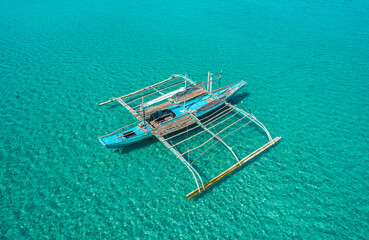 Wall Mural - Aerial drone view of traditional philippine boat bangka anchored in the bay with clear and turquoise water on sunny day. Boat in the tropical lagoon. El Nido, Palawan island, Philippines.