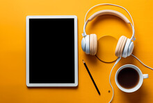 Tablet With Blank Screen Beside Headphones And Coffee On Vibrant Yellow.

