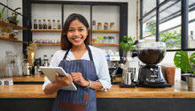 An Asian Female Barista Wears An Apron And Holds A Tablet Computer Coffee Menus At A Counter Bar With A Smiling Face