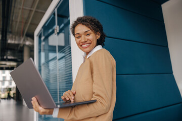 Pretty female freelancer working on laptop while standing on modern coworking background