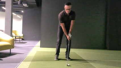 Wall Mural - Professional male golfer holding club playing golf indoors on golf simulator concept