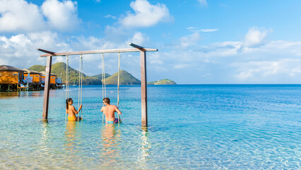 Wall Mural - Couple in a swing on the beach of the tropical Island Saint Lucia or St Lucia Caribbean, holiday vacation. men and women on a luxury vacation