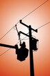 Silhouette of power lineman uses a clamp stick grip all type to install the line cover on energized high-voltage electric power lines. To change the lightning arresters that is damaged.