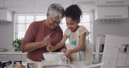 Wall Mural - Baking and cooking with a grandmother and her granddaughter during a visit at home for bonding and spending quality time together. Grandparent teaching her grandchild how to bake in the kitchen