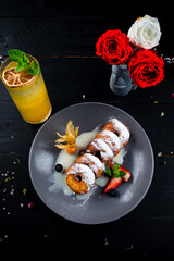 Wall Mural - Donuts with sweet sauce, strawberries, blueberries, physalis, powdered sugar and orange lemonade.