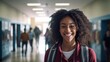 Happy black teenage girl in a high school hallway looking at camera