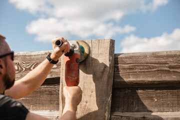 Man work on holiday repairing and renovating a country house - summer chores in the backyard and garden - power tool work