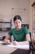 © snowing12 - Young asian student women use calculator with finance to writing notes in notebook and doing homework after studying lecture webinar in online class and learning knowledge remote education from home