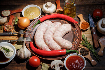 Raw sausages for frying with different spices, sauces and vegetables, barbecue sausages