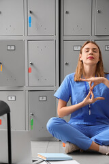 Wall Mural - Female medical intern meditating near locker at university