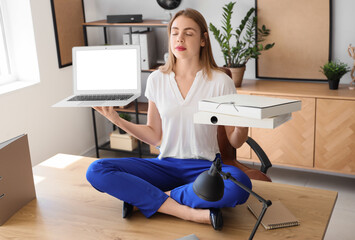 Poster - Young businesswoman with laptop and folders meditating on table in office