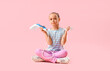 Little girl with steamer sitting on pink background