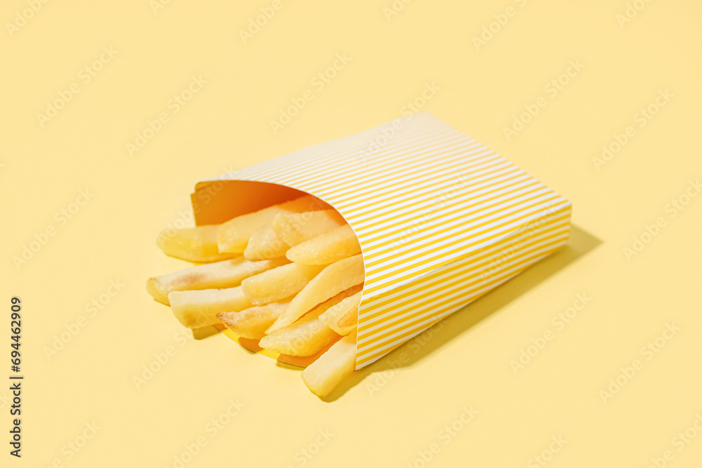 Paper box with french fries on yellow background