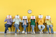 © Pixel-Shot - Applicants holding paper sheets with different marks near yellow wall in room